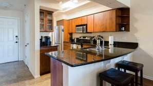 Une cuisine moderne avec des meubles en bois, un réfrigérateur en acier inoxydable, un four à micro-ondes et un grand îlot central doté d’un évier.