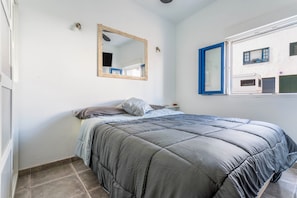 A bedroom with a bed, a mirror, and a window with blinds. - Holiday Home ‘Caleta de Caballo’ directly by the Sea with Sea View & Terrace (Famara)