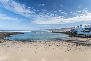 A coastal beach with white buildings, clear blue sky, and calm sea. - Holiday Home ‘Caleta de Caballo’ directly by the Sea with Sea View & Terrace (Famara)