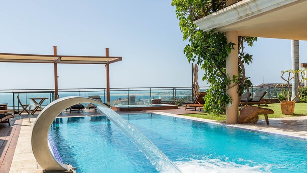 A pool with a water feature, lounge chairs, and a view of the city. - Villa "Albella" with Sea View, Garden, Terraces, Pool, Sauna, Whirlpool & Gym (San Bartolone de Tirajana)