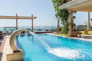 A pool with a water feature, lounge chairs, and a view of the city.