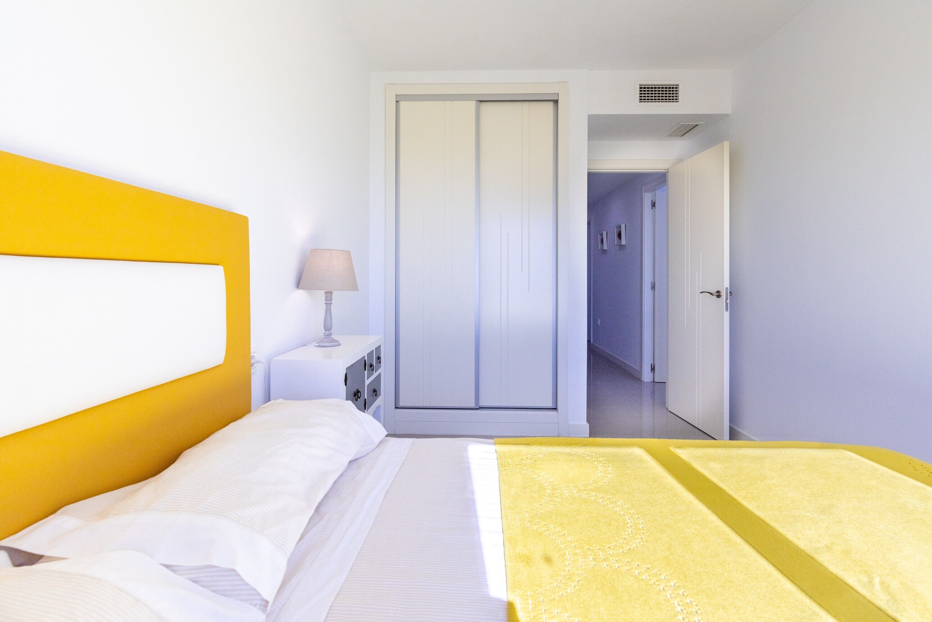 A hotel room with a bed, a nightstand, a lamp, and a wardrobe.