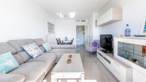 Ein modernes Wohnzimmer mit Sofa, Couchtisch, Fernseher und einer Glasschrank.