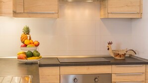 Una cocina con armarios de madera, un horno de acero inoxidable y un frutero en la encimera.