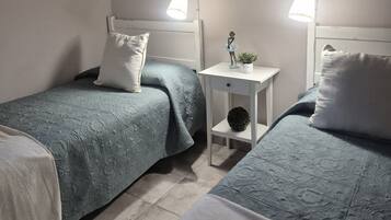 Un dormitorio con dos camas, una mesita de noche, una lámpara de pared y un cuadro enmarcado.