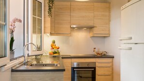Una cocina moderna con armarios de madera, un lavamanos de acero inoxidable y un horno empotrado.