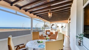 A covered outdoor dining area with a table, chairs, and a view of the beach. - Villa "Rústica" close to the Beach with Sea and Mountain Views, Pool & Terraces (Matagorda)