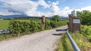 Un sendero de grava que conduce a una tienda de vinos con un letrero, rodeada de vegetación y un cielo despejado.