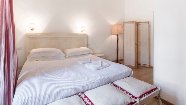 Ein Hotelzimmer mit Bett, Nachttischlampen, einem Spiegel und einer Tür.