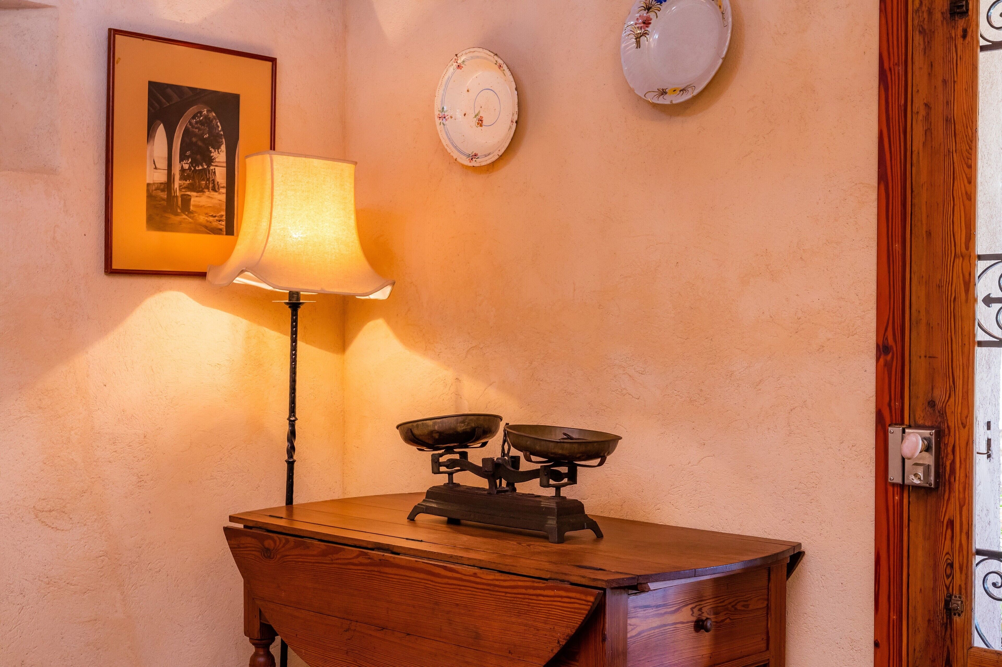 A wooden desk with a scale, a lamp, and a framed picture on the wall.