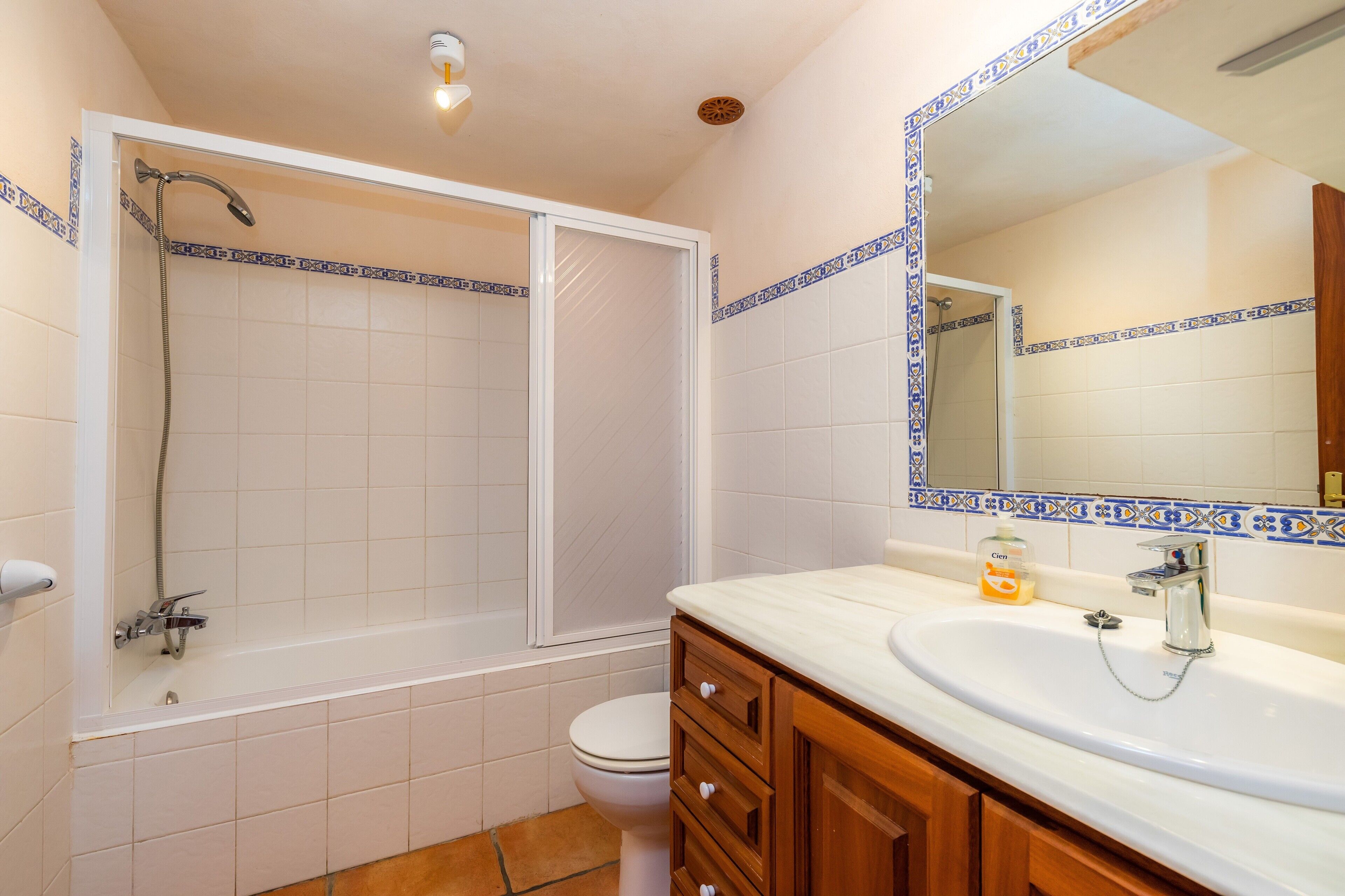 Een badkamer met een bad, toilet, wastafel en spiegel.