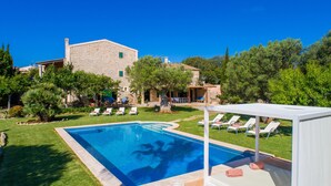 A swimming pool with lounge chairs, a stone building, and surrounding greenery. - Stunning Holiday Home “Finca Rafal” with Garden, Pool, Terraces & WiFi; Parking Available (Son Servera)