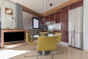Une cuisine moderne avec un îlot central, des chaises jaunes et des appareils électroménagers en acier inoxydable.