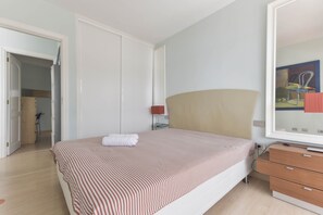 Une chambre à coucher avec un lit, une commode, une table de chevet et un tableau accroché au mur.