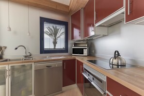 Una cocina moderna con lavavajillas, microondas, hervidor y encimeras de madera.