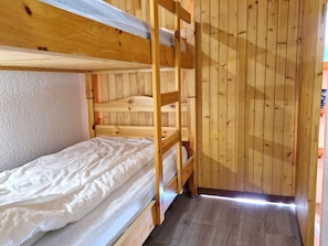 A bunk bed room with wooden walls and a wooden floor.
