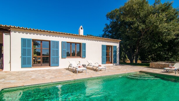 Une maison avec une piscine, des volets bleus et un toit recouvert de tuiles.