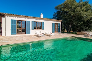 Una casa con piscina, contraventanas azules y tejado de tejas.