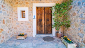 Un bâtiment en pierre avec une porte en bois, une petite fenêtre et des plantes en pot.