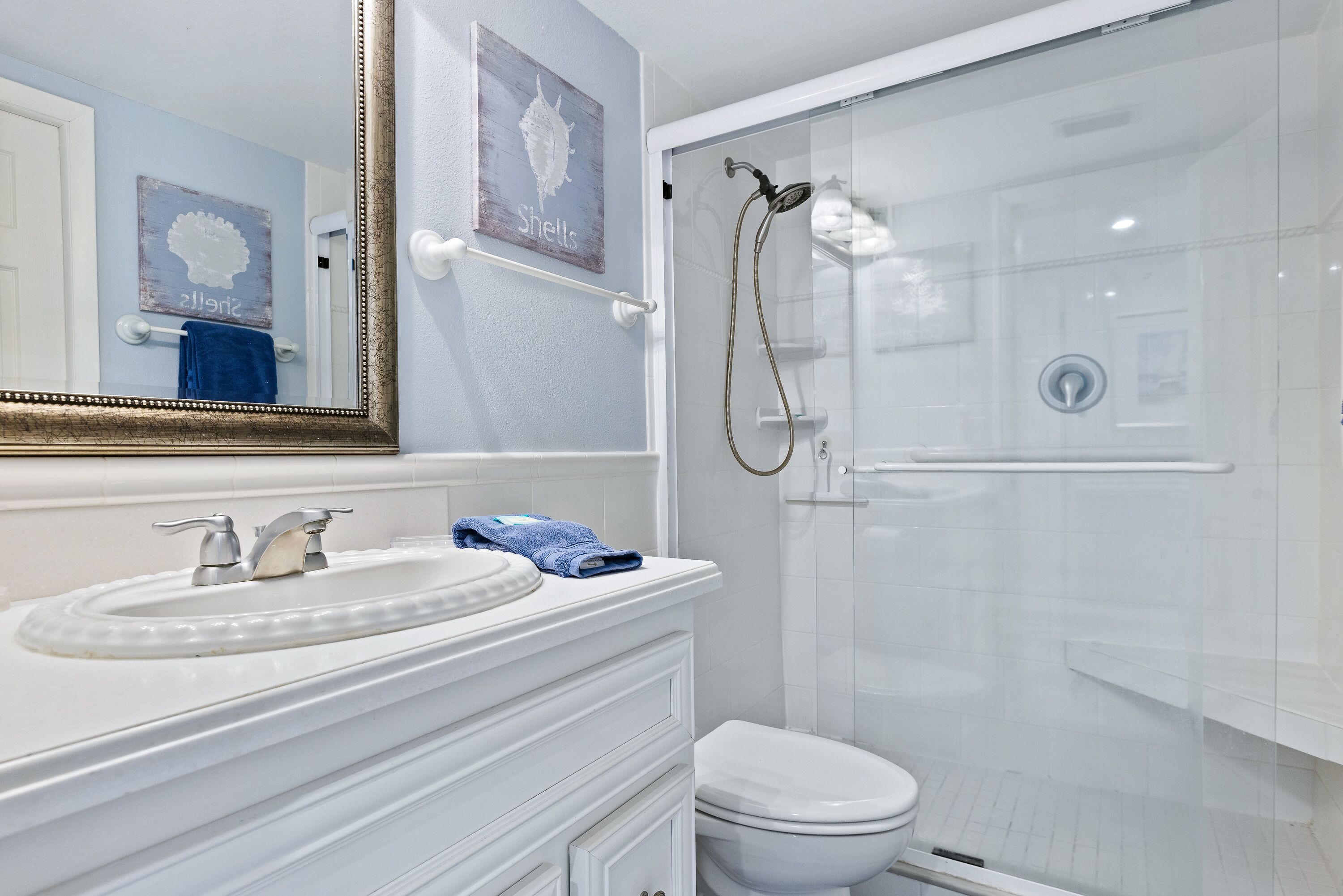 Une salle de bain avec un lavabo blanc, des toilettes et une douche à parois de verre.