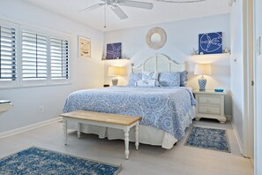 Ein Schlafzimmer mit einem Bett, Nachttischen, einer Bank und einem Deckenventilator.
