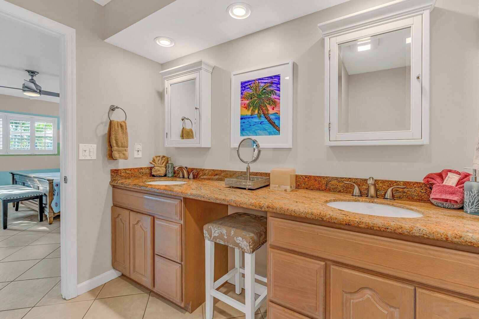 A modern bathroom with two sinks, a large mirror, and a painting of a beach scene.