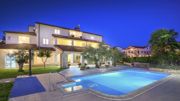A large house with a swimming pool, a covered patio, and a well-maintained garden.