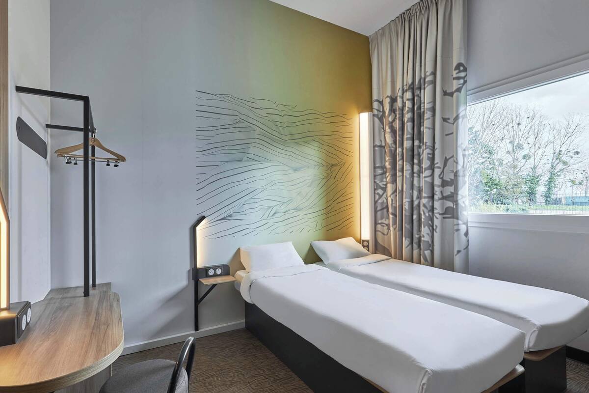 A hotel room with a bed, bedside table, and a desk.