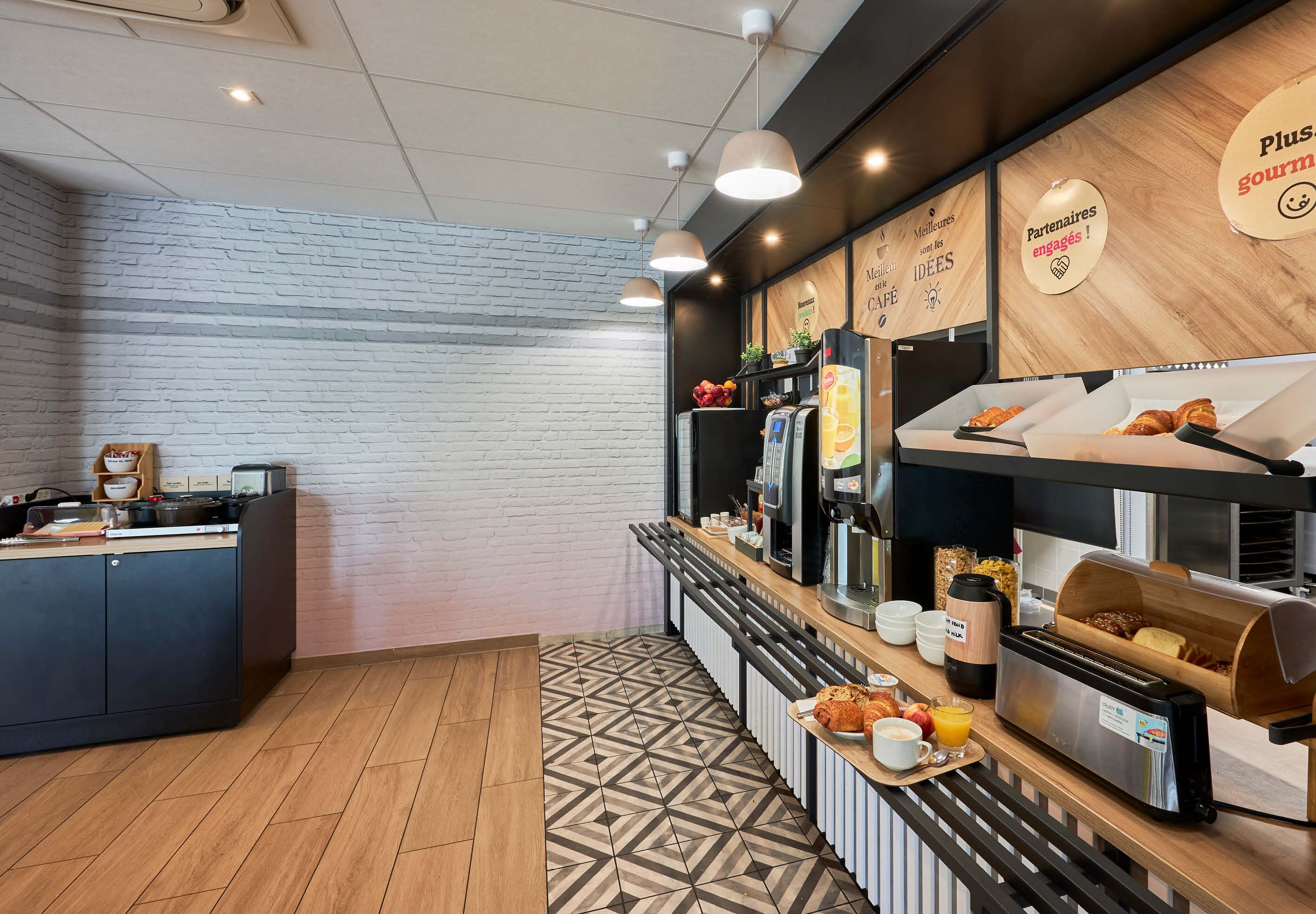 A modern café with a brick wall, wooden counter, and various food items displayed.