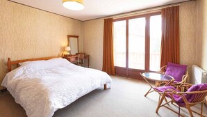 A hotel room with a bed, a desk, a chair, and a window with curtains.