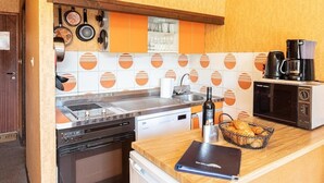 A kitchen with a stove, microwave, coffee maker, and a basket of bread on the counter.