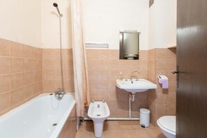 Een bad/douchecombinatie, handdoeken, zeep, toiletpapier