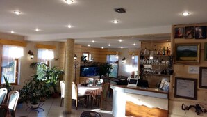 A cozy bar area with wooden decor, a counter with a laptop, and various bottles and glasses. - Byczy Rog Noclehy Na Hranici (Kraliky)