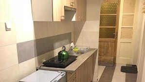 A narrow kitchen with a refrigerator, sink, and a small trash bin. - Byczy Rog Noclehy Na Hranici (Kraliky)