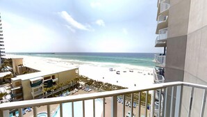 Ein Hotel direkt am Strand mit Pool, Blick auf den Strand und einem Pier in der Ferne.