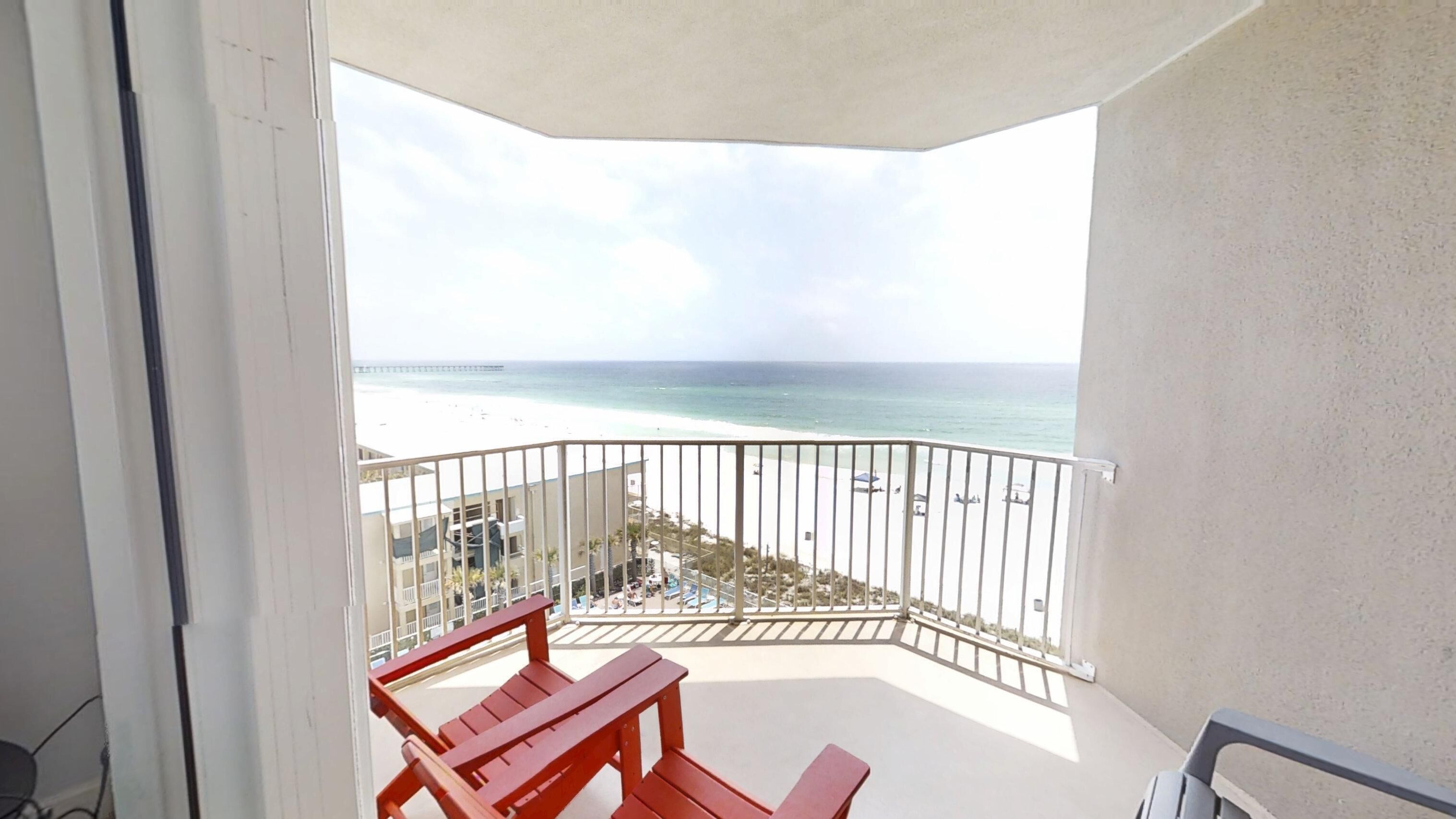 A balcony with a view of the beach and ocean.