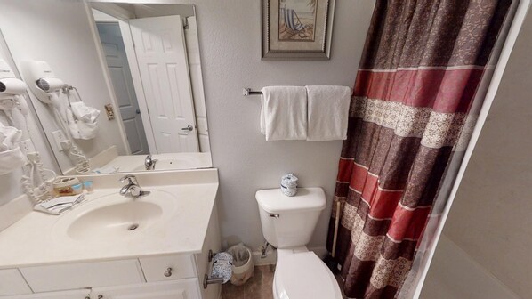 A bathroom with a white sink, a toilet, a shower curtain, and a towel rack.