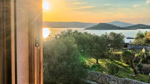 Vista desde una ventana sobre un lago con una montaña al fondo, rodeado de vegetación.