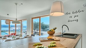 Una cocina moderna con una isla grande, un bol de fruta y una tabla de cortar con rodajas de lima.