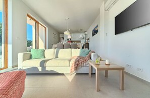 A modern living room with a sofa, a coffee table, and a TV mounted on the wall.