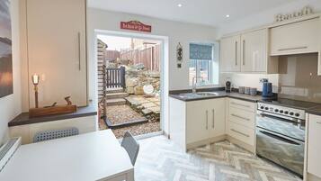 A modern kitchen with a herringbone floor pattern, a built-in oven, and a sink area.