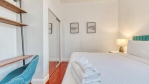 A hotel room with a bed, a chair, a desk, and artwork on the wall. - Stairway | 3BR Apt w W/D Ideal for Groups (Philadelphia)