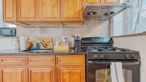 A kitchen with wooden cabinets, a gas stove, and a microwave. - Stairway | 3BR Apt w W/D Ideal for Groups (Philadelphia)
