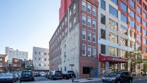 A multi-story building with a red and white facade, a visible entrance, and a sign reading "211 North 8th Street". - Stairway | 3BR Apt w W/D Ideal for Groups (Philadelphia)