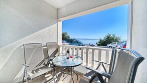 Ein Balkon mit Tisch und Stühlen, mit Blick auf einen Parkplatz und ein Gewässer.