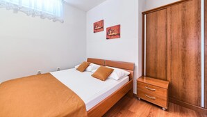 Ein Schlafzimmer mit einem hölzernen Bett, einem Kleiderschrank und zwei Bildern an der Wand.