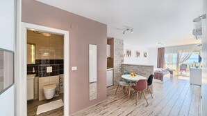 Una habitación de hotel moderna con comedor, cocina y balcón con vistas.