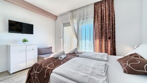 A modern hotel room with a bed, a TV, a desk, and a window with curtains. - PANORAMIC APARTMENT WITH SEE VIEW (Podstrana)