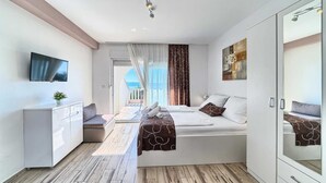 A modern hotel room with a bed, a desk, a TV, and a balcony with a view. - PANORAMIC APARTMENT WITH SEE VIEW (Podstrana)
