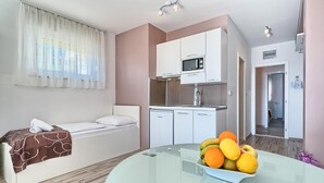 A compact hotel room with a single bed, kitchenette, and a dining area with a fruit bowl. - PANORAMIC APARTMENT WITH SEE VIEW (Podstrana)